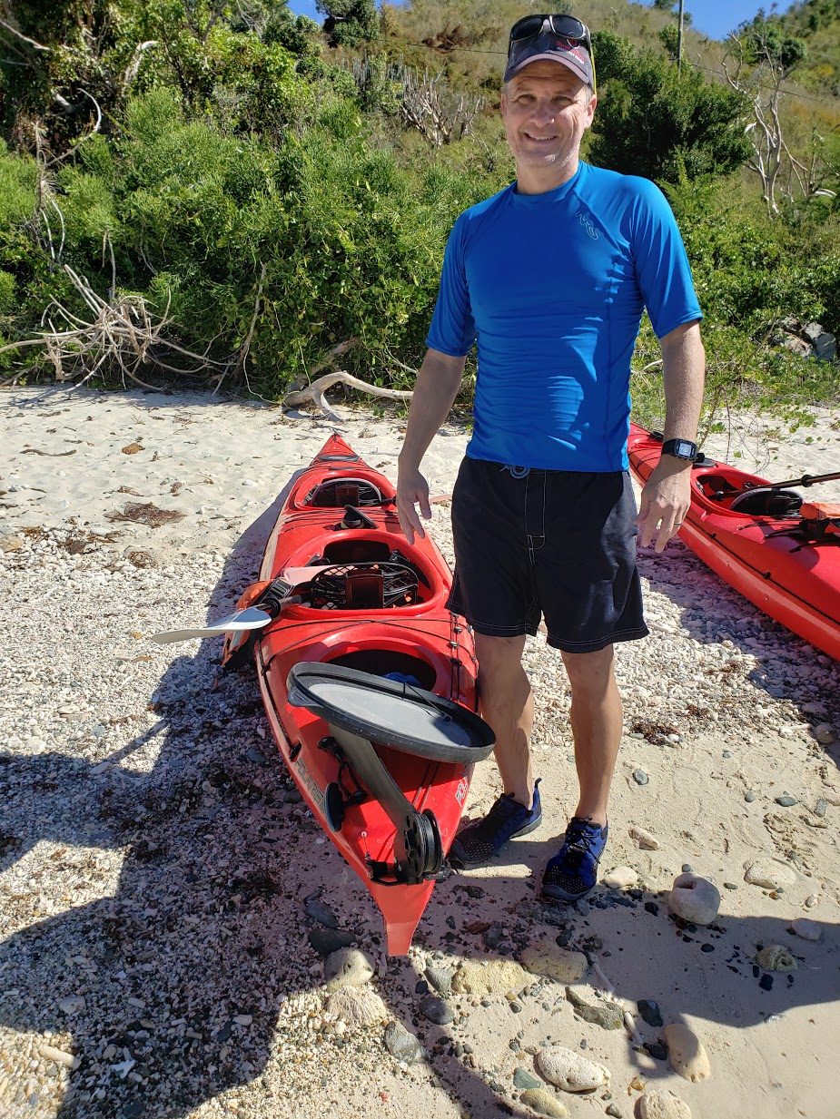 Daniel Erwin on a beach with sea kayaks